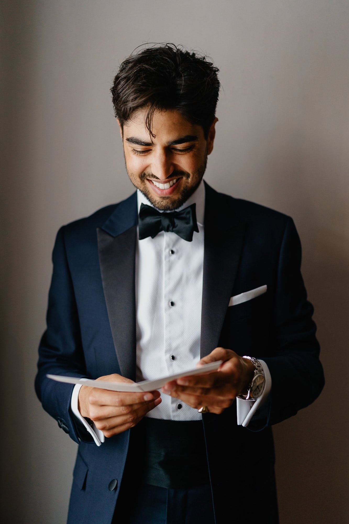 Groom reading a heartfelt love message card from his bride on their wedding day.