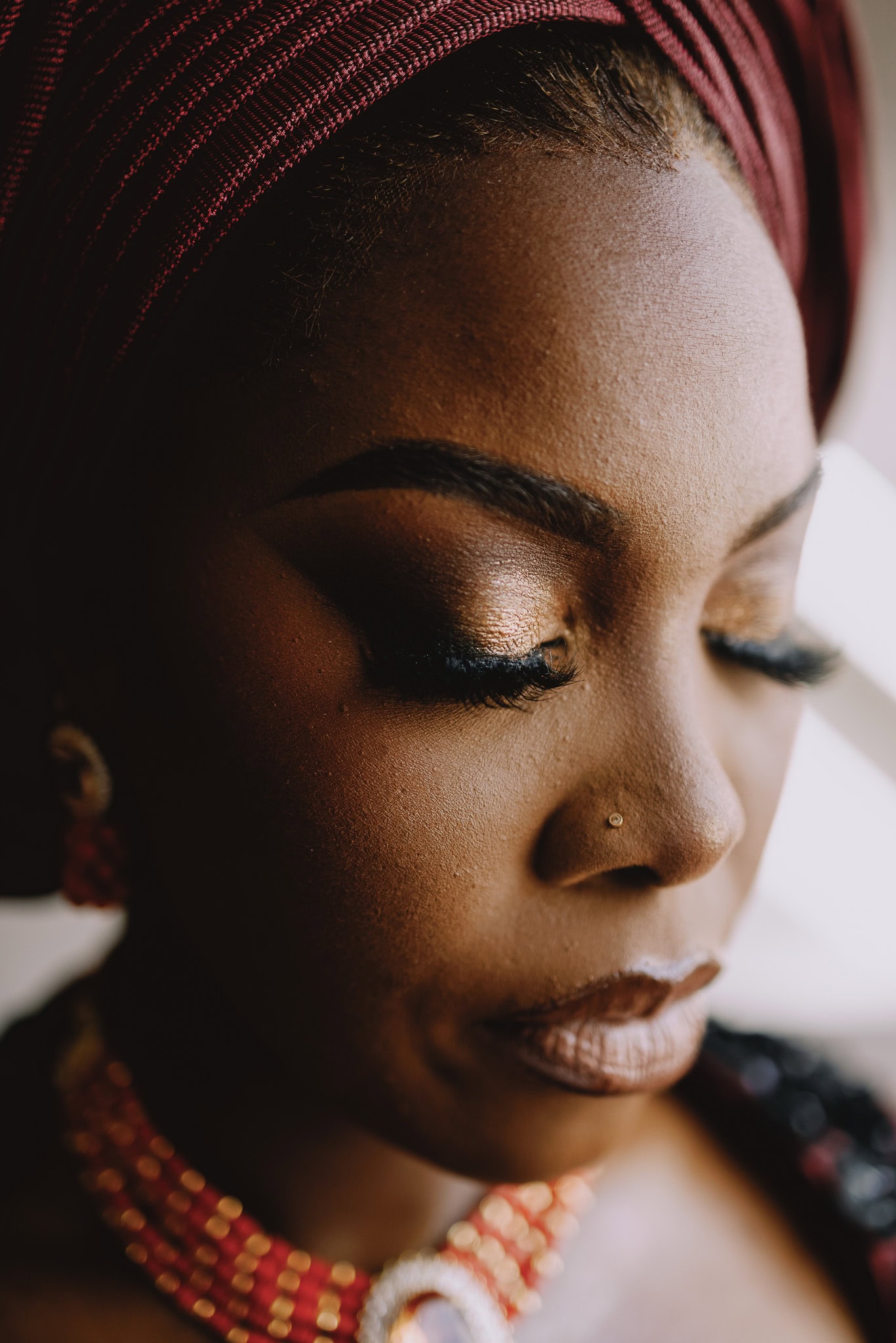 Close-up of a bride with traditional headwrap and jewelry, part of a wedding photography portfolio.