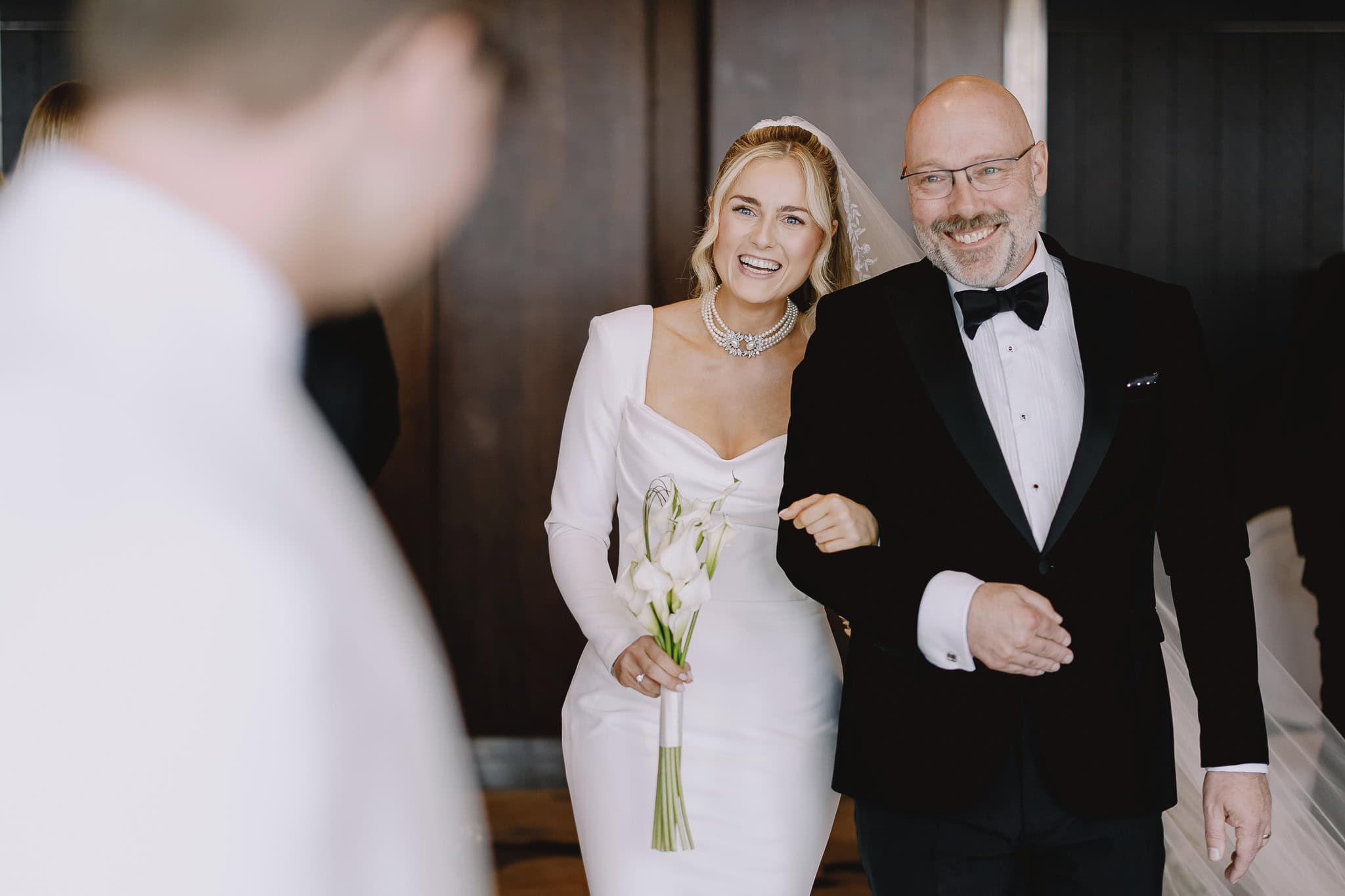Bride and father walking down the aisle, smiling. Wedding photography portfolio.