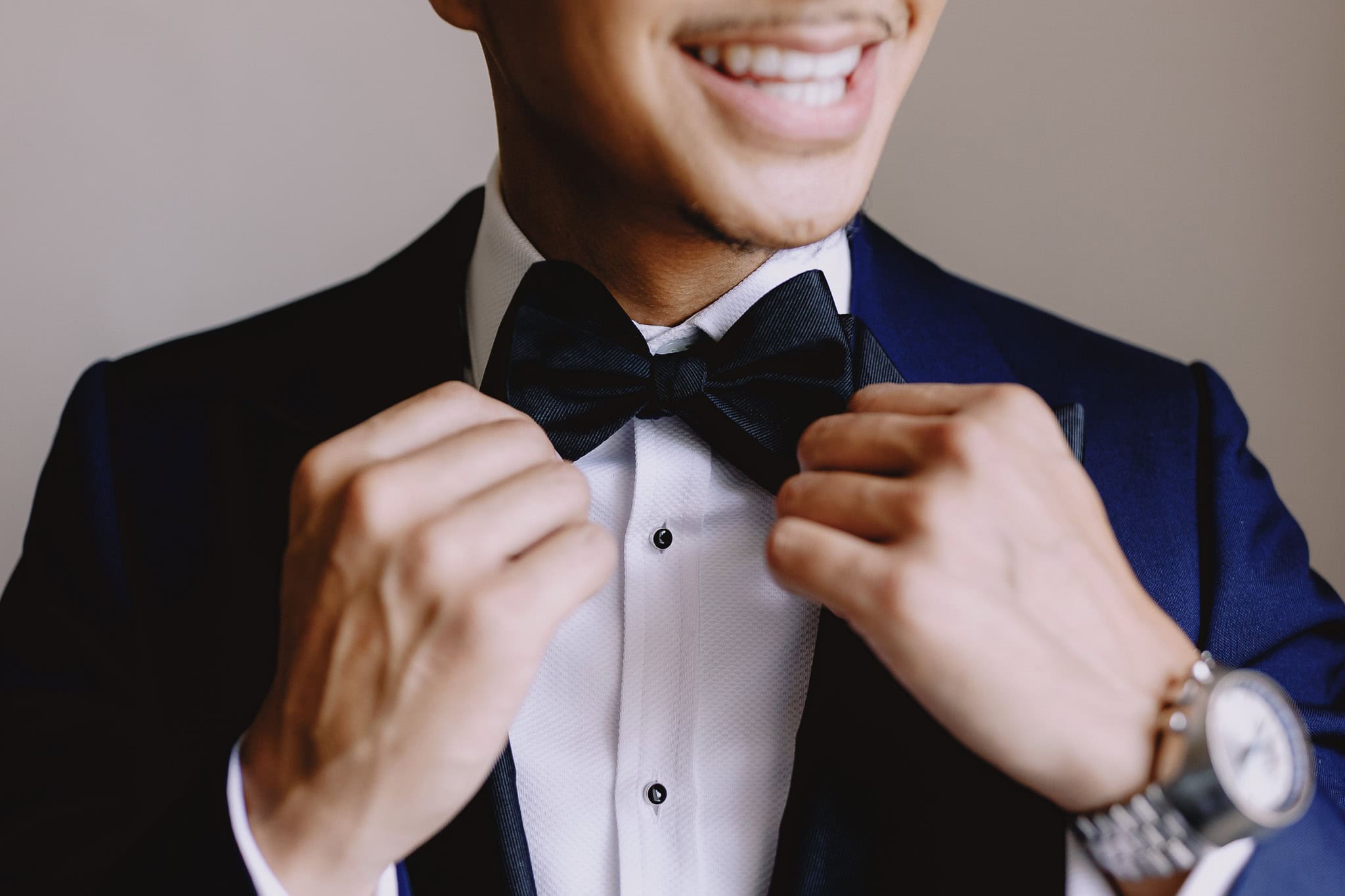 Groom adjusting his bow tie.