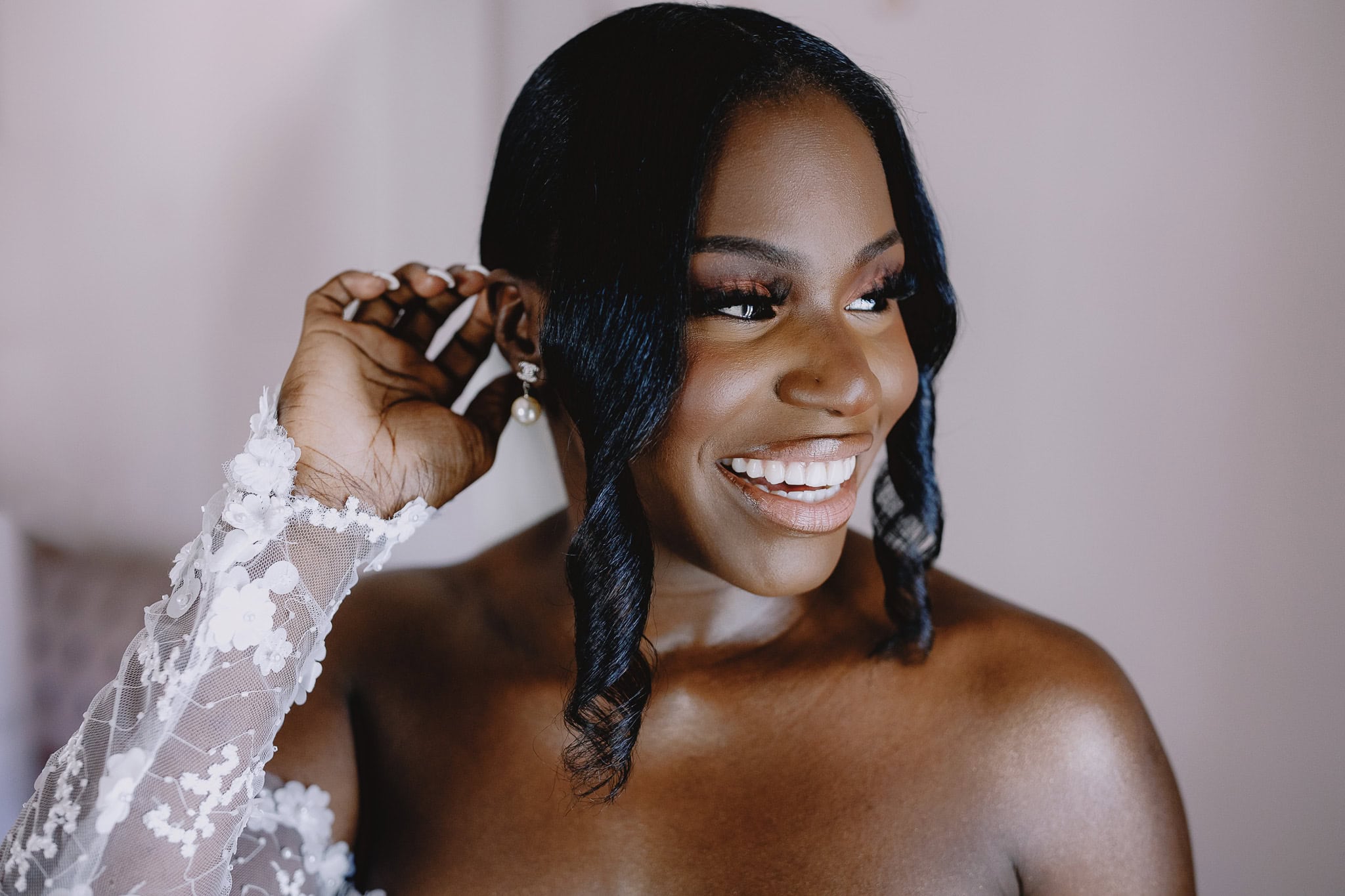 Smiling Black bride adjusts her pearl earring.