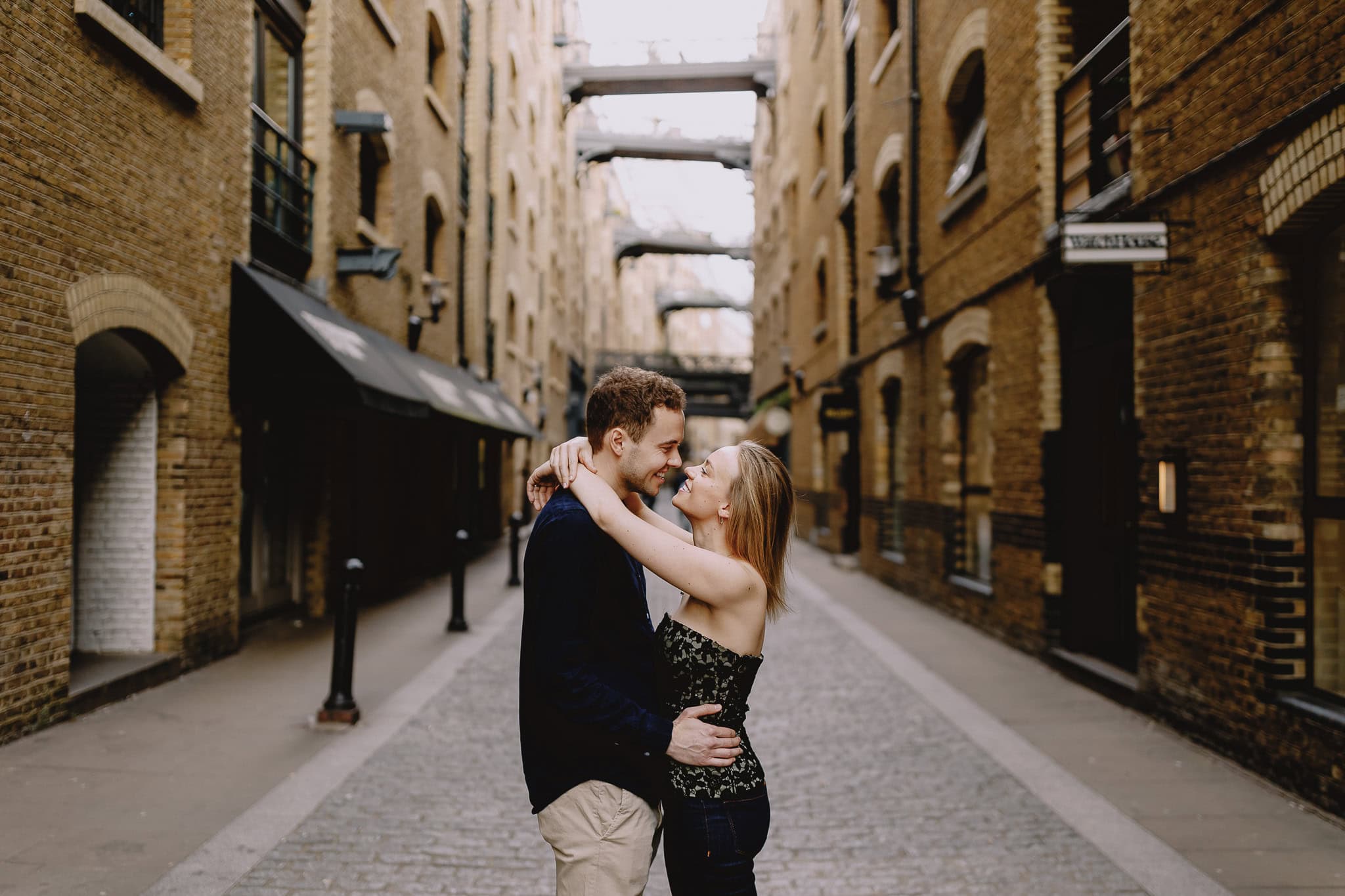 Couple embracing in a brick alleyway, editorial wedding photography style.