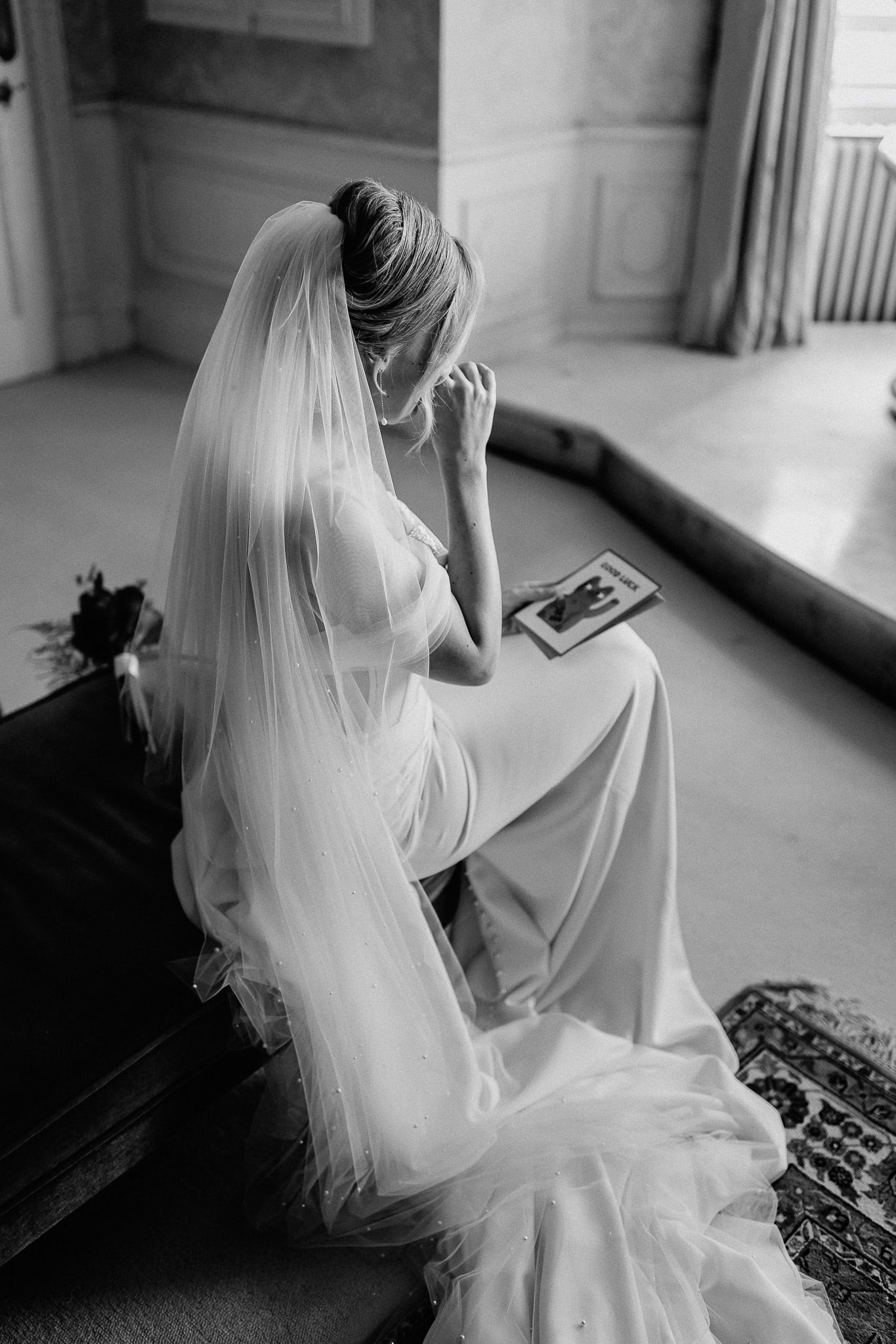 Bride reading a "Good Luck" card before her wedding. Editorial wedding photography.