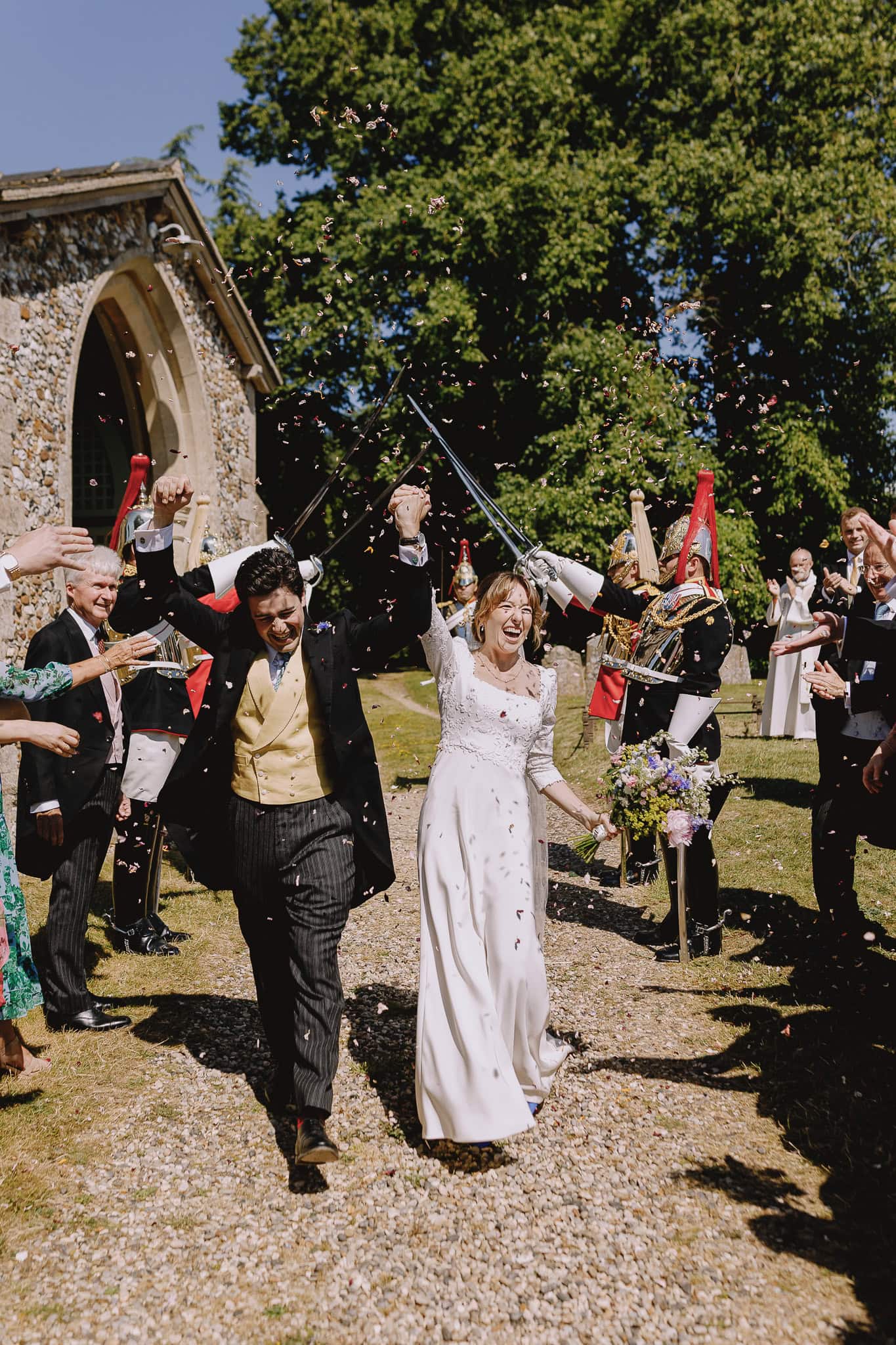 Bride and groom exit wedding under swords, editorial wedding photography.