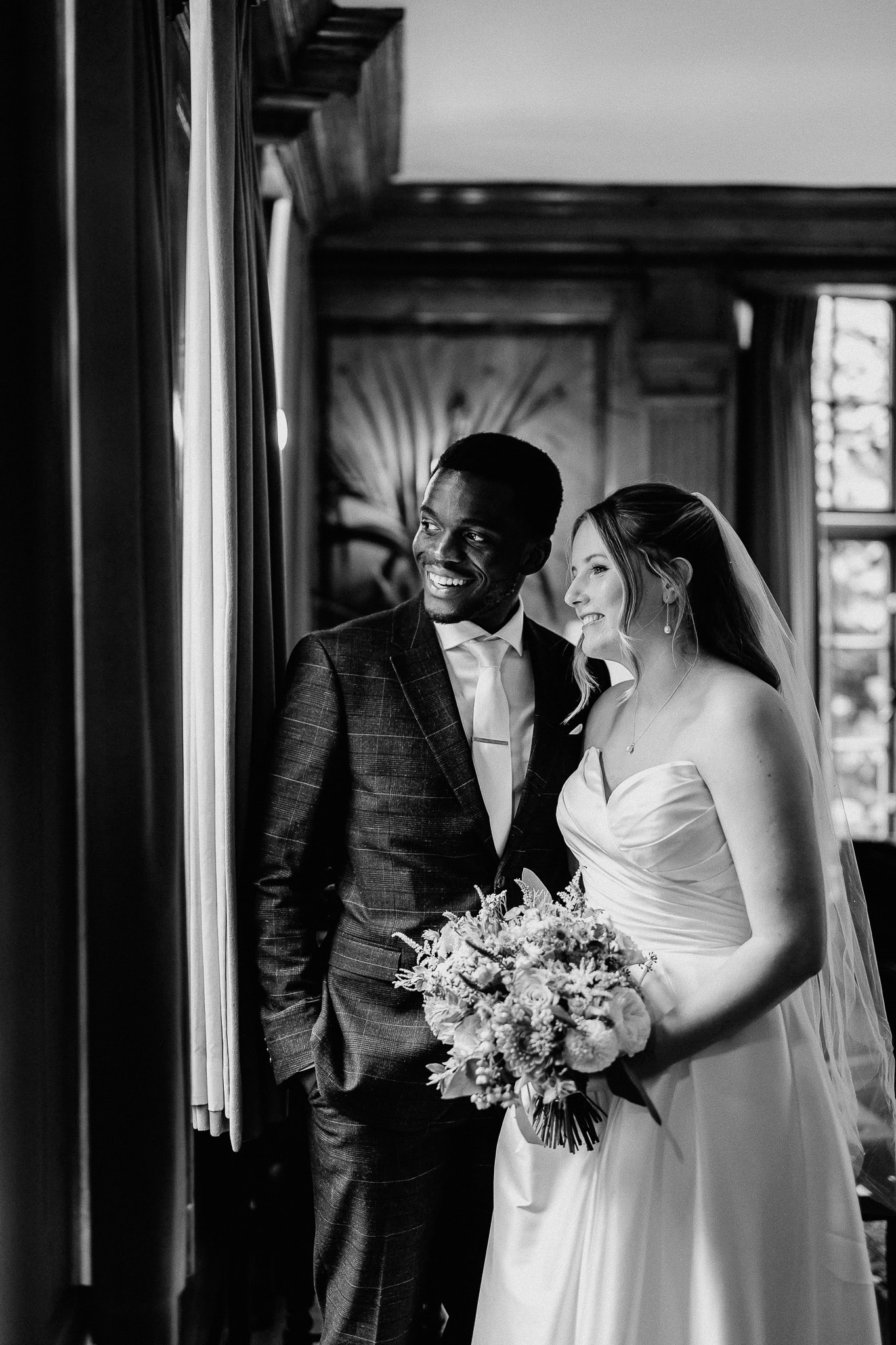 Smiling bride and groom in elegant attire during editorial wedding photography session.