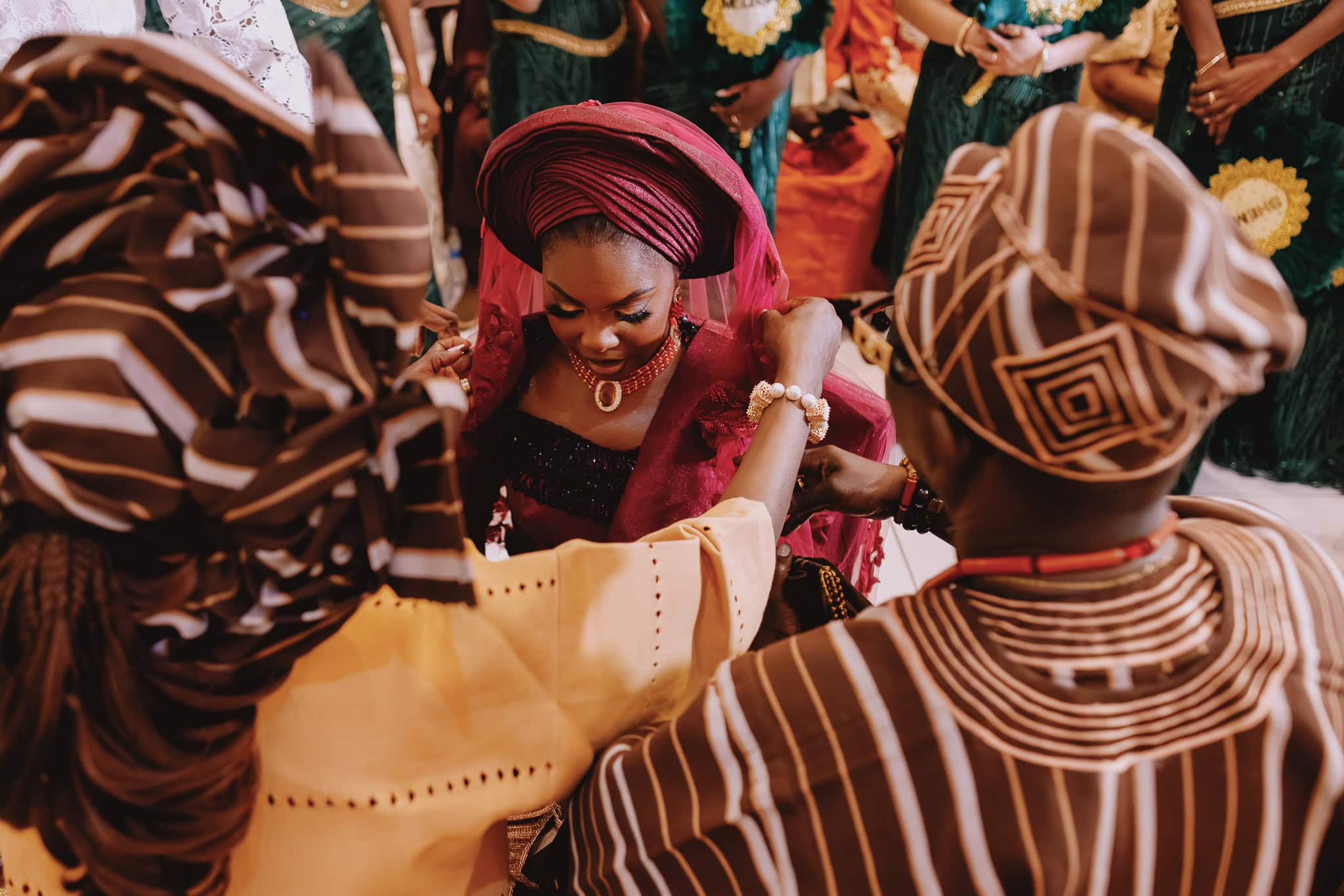 Bride in traditional outfit surrounded by family at a cultural wedding