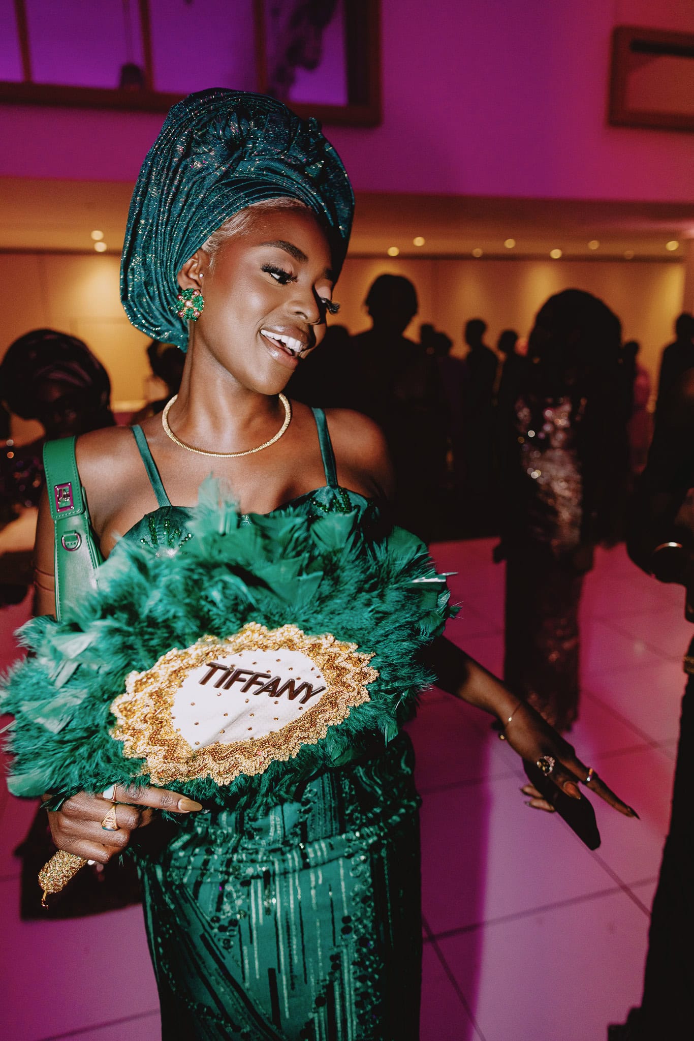 Woman in green dress with "Tiffany" fan at party.