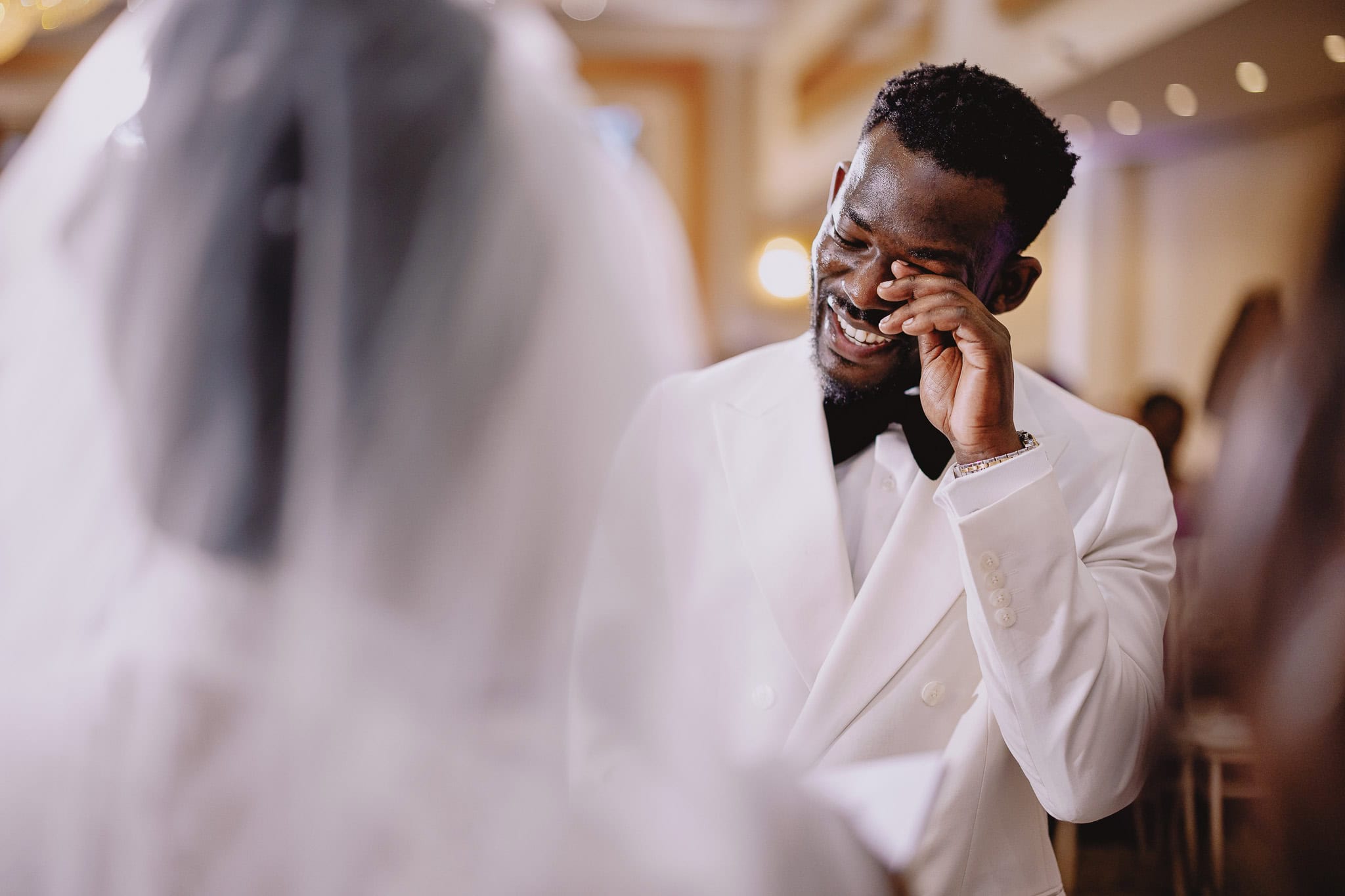 Emotional groom wiping tears at wedding. Happy moment.