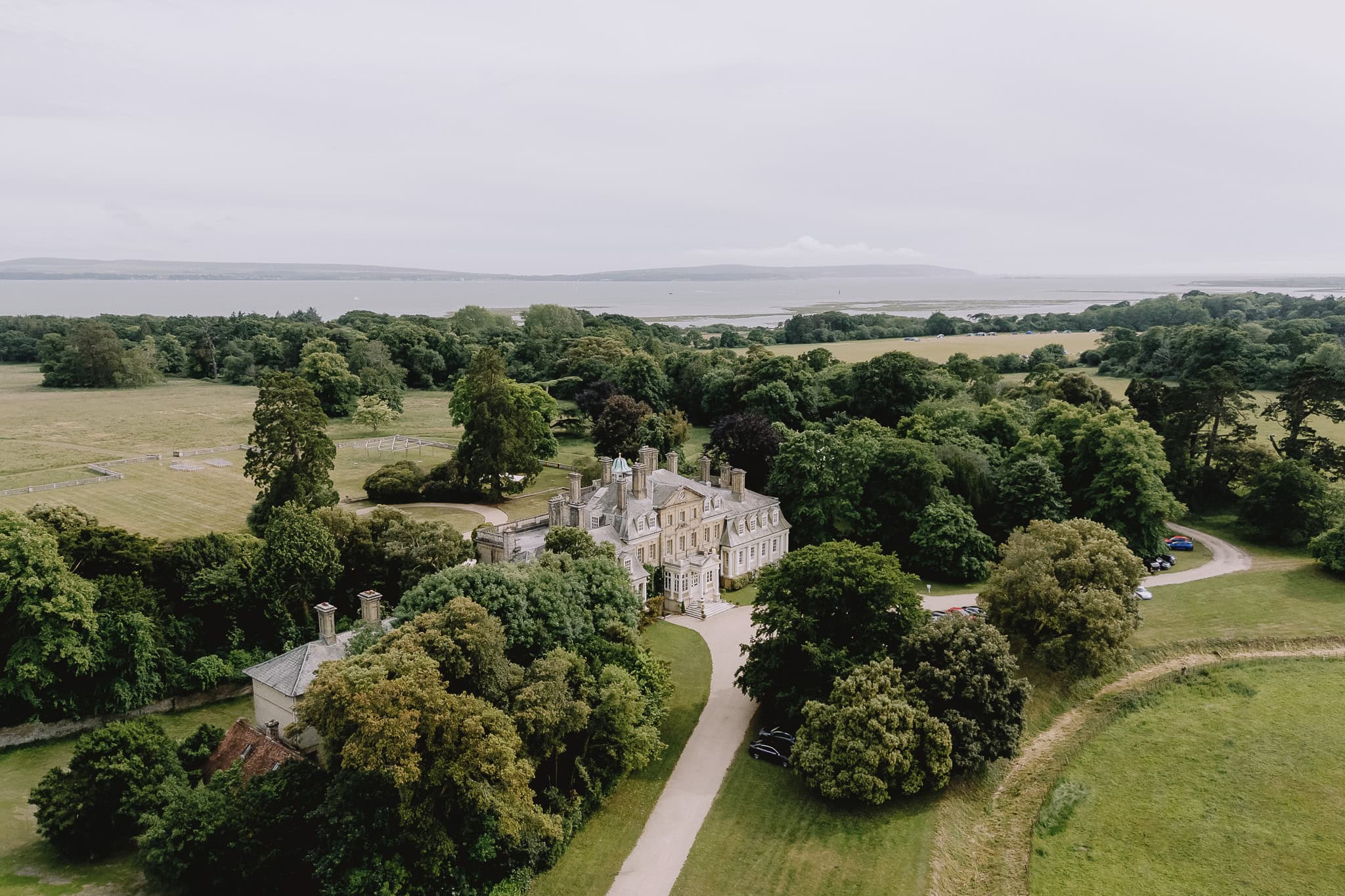 Aerial view of grand estate with lush gardens and coastal backdrop.