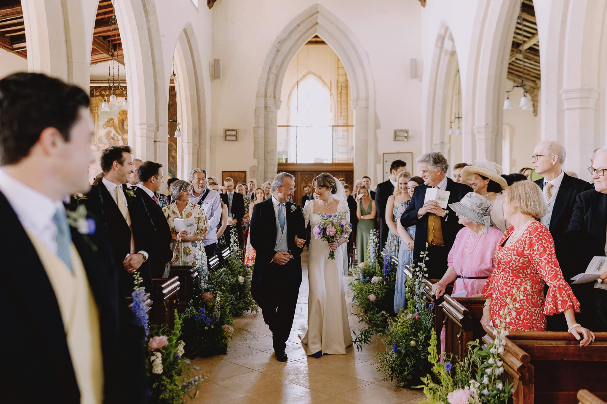 Bride walks down the aisle with her father in a church wedding.