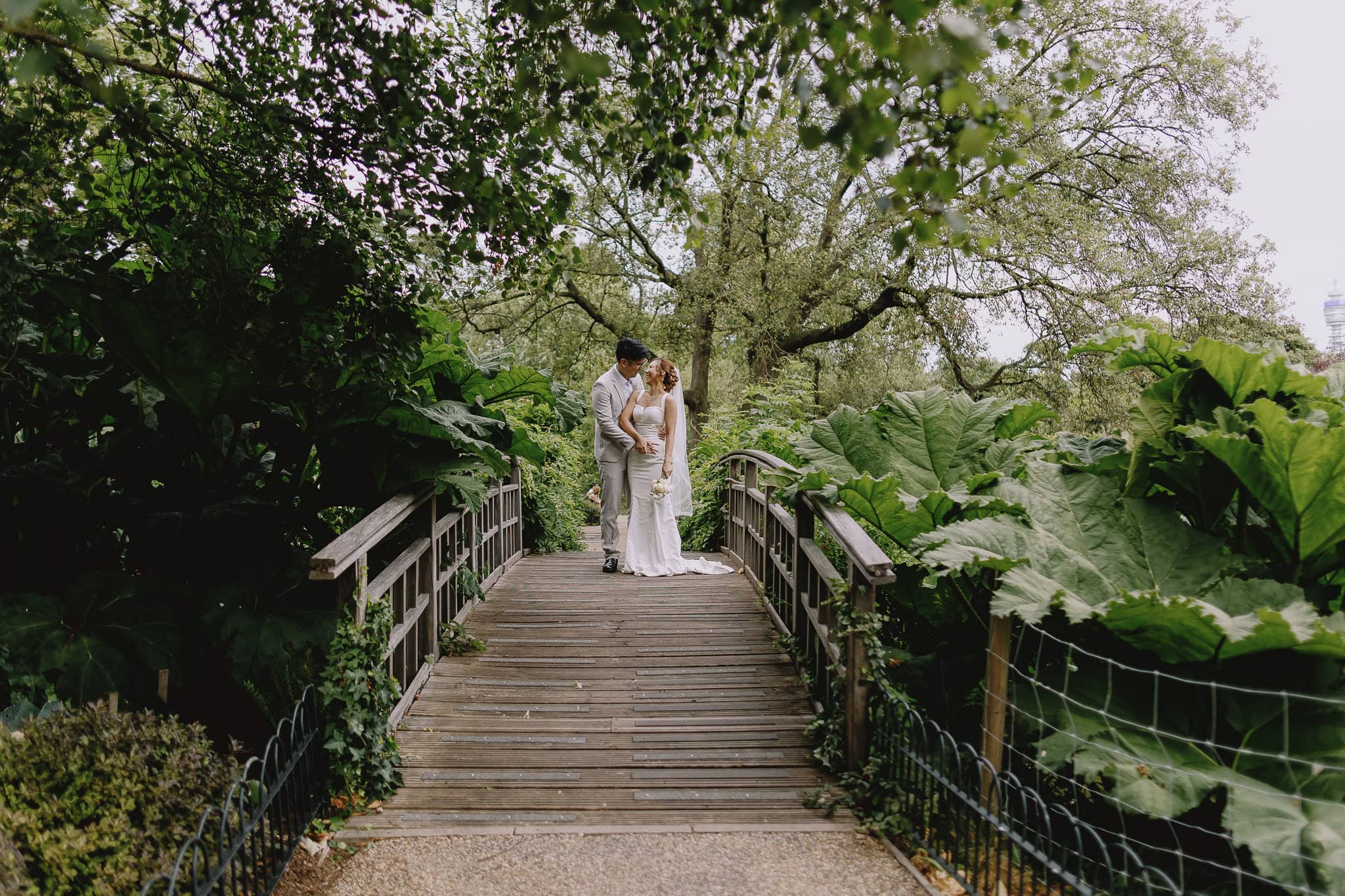 Wedding photography portfolio: Couple on a wooden bridge in a lush garden.