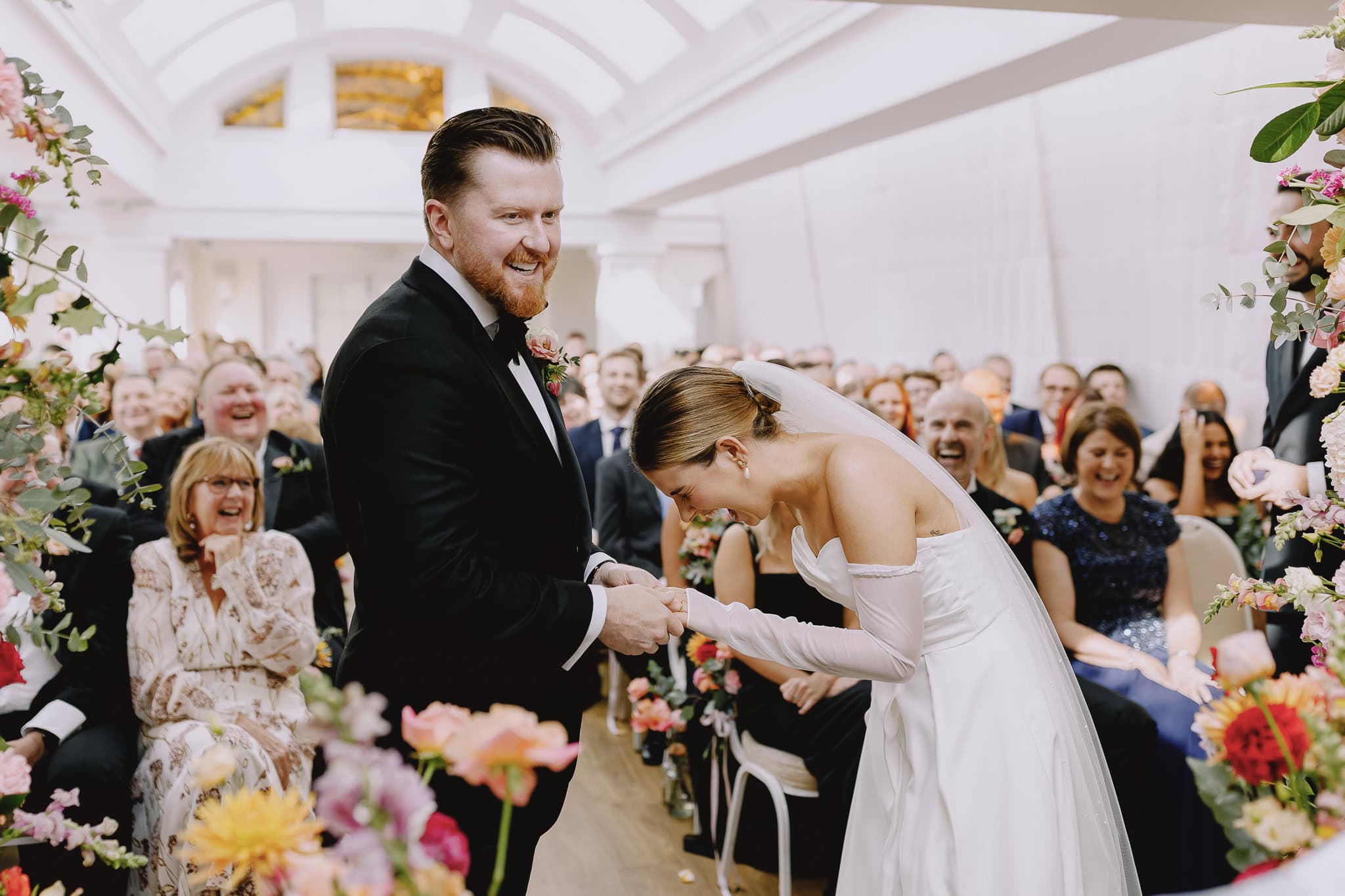 Bride bows to groom during wedding ceremony, joyful guests. Wedding Photography Portfolio.