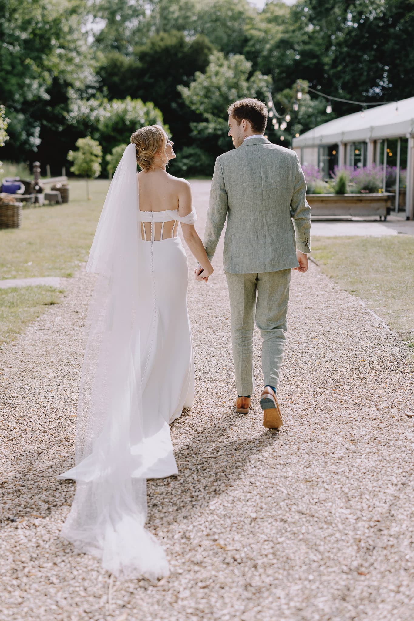 Bride and groom walking hand-in-hand at their garden wedding.