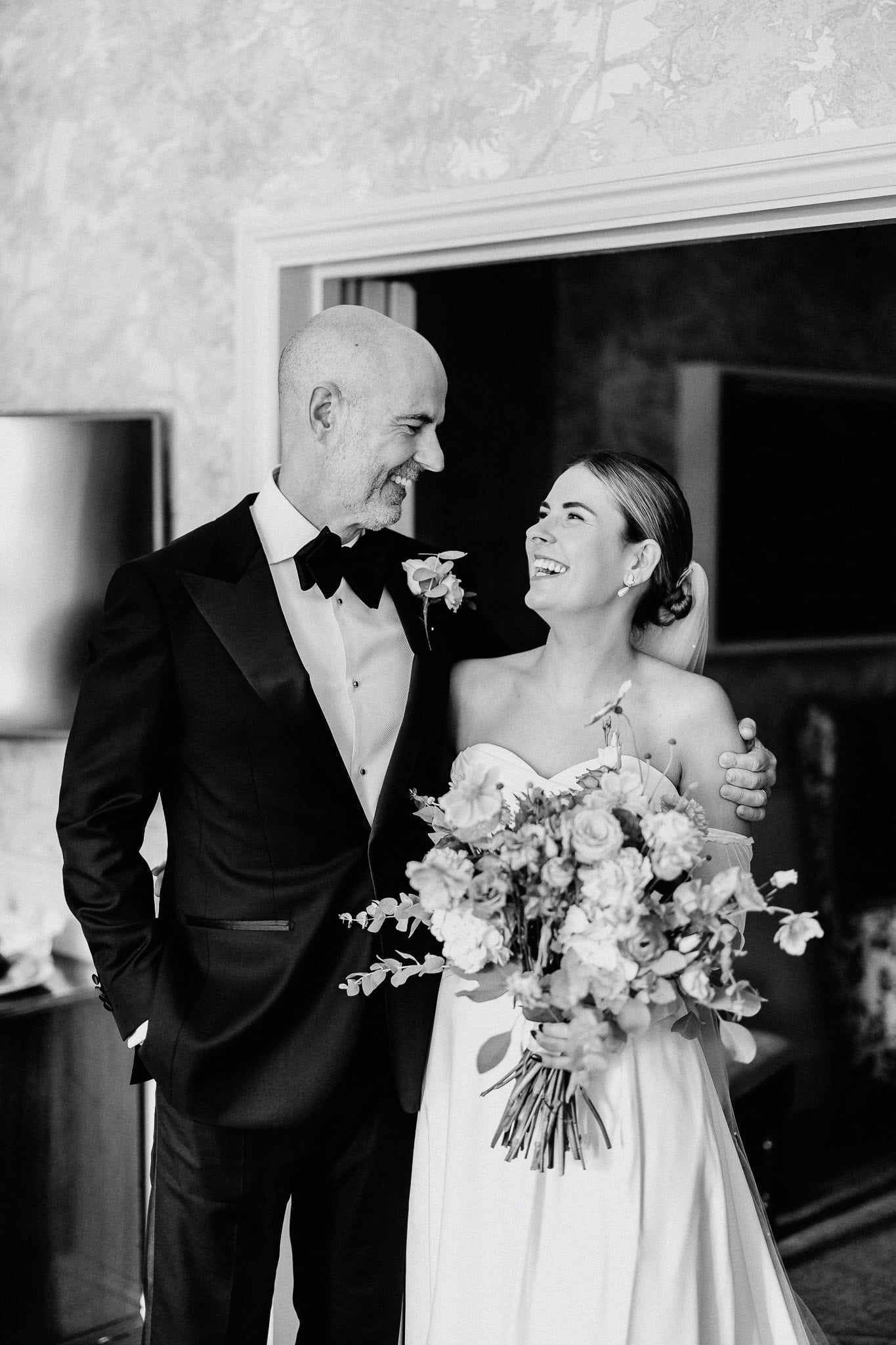 Happy bride and groom in tuxedo and wedding dress share a loving glance.