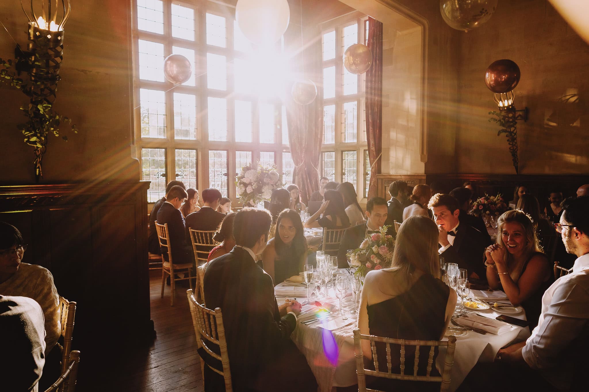 Guests dining at a wedding reception with sunlight streaming through windows