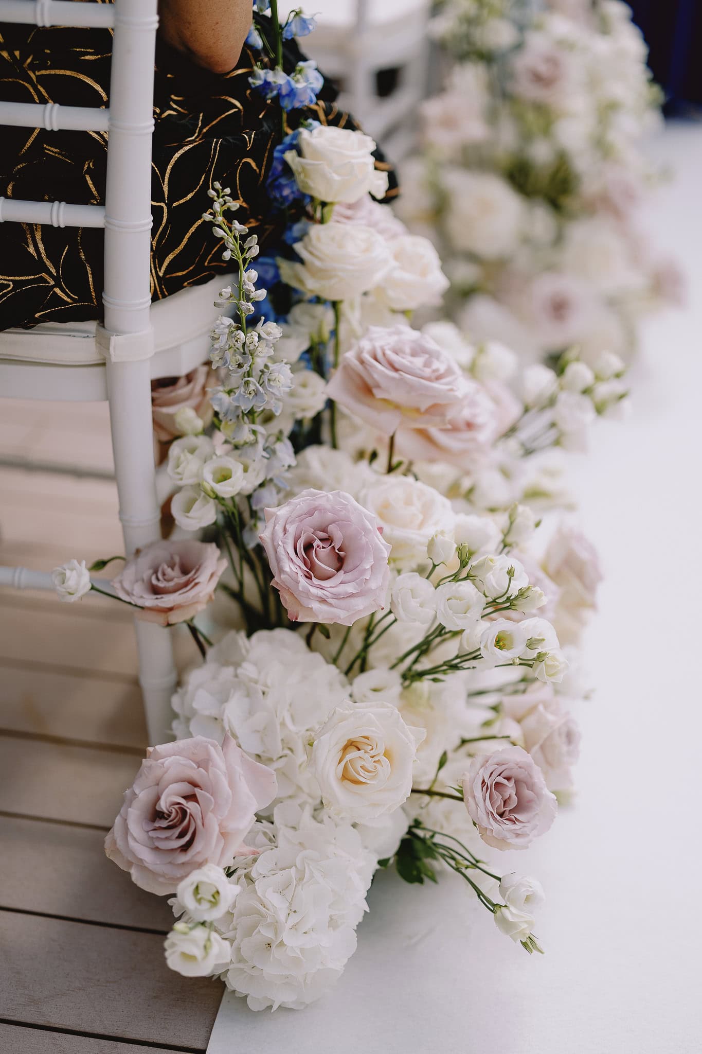 Elegant wedding chair adorned with blush and white floral arrangement.