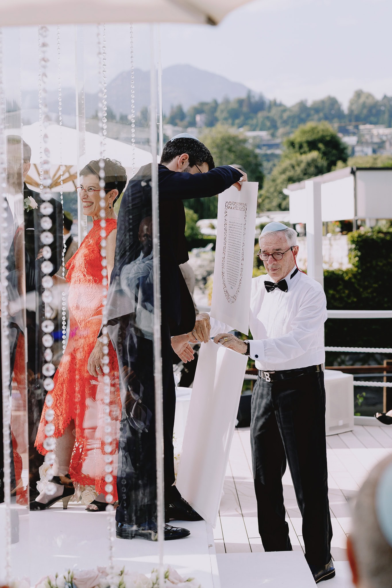 Here are a few examples of blog titles and keywords that could be used to create the alt text: **Example 1** Blog Title: Jewish Wedding Traditions SEO Keywords: Jewish wedding, ketubah signing, wedding ceremony **Example 2** Blog Title: Destination Weddings in Italy SEO Keywords: Italian wedding, Lake Como wedding, outdoor ceremony **Example 3** Blog Title: Modern Wedding Ideas SEO Keywords: Clear chuppah, modern wedding, outdoor wedding Now, please provide the alt text and explanation.