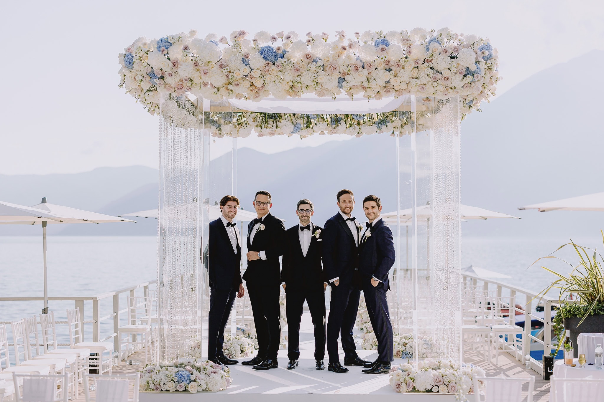 Groomsmen under floral chuppah at outdoor wedding ceremony