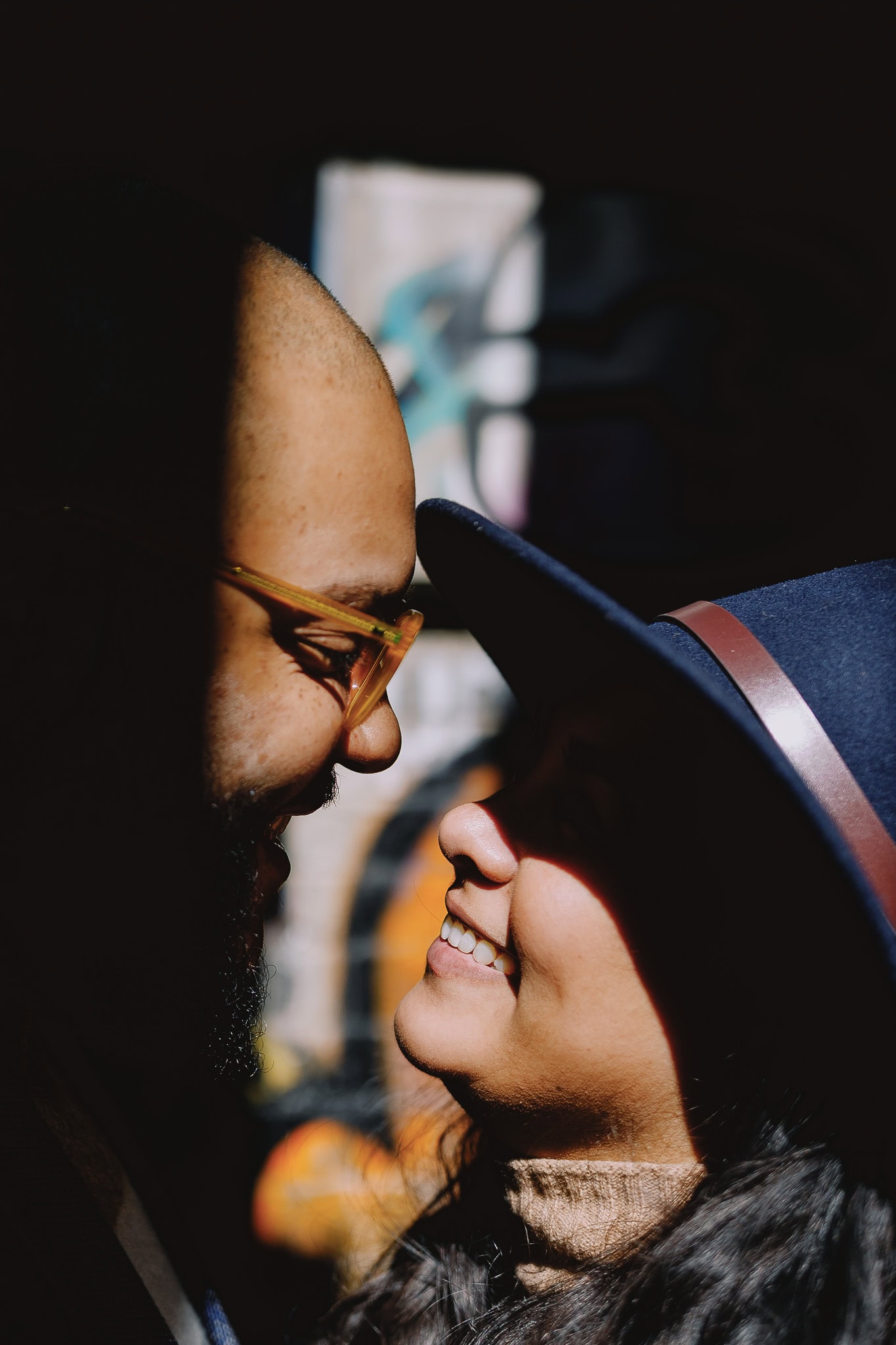 Couple gazing at each other, partially shadowed, woman in hat smiling