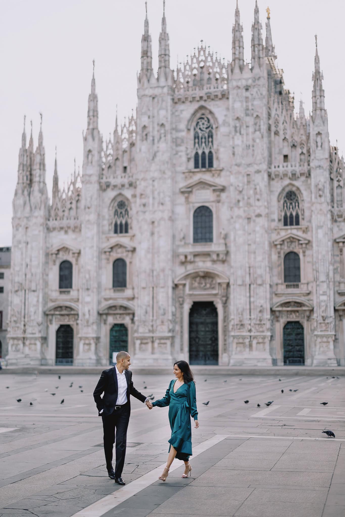 Couple holding hands in front of Milan Cathedral.