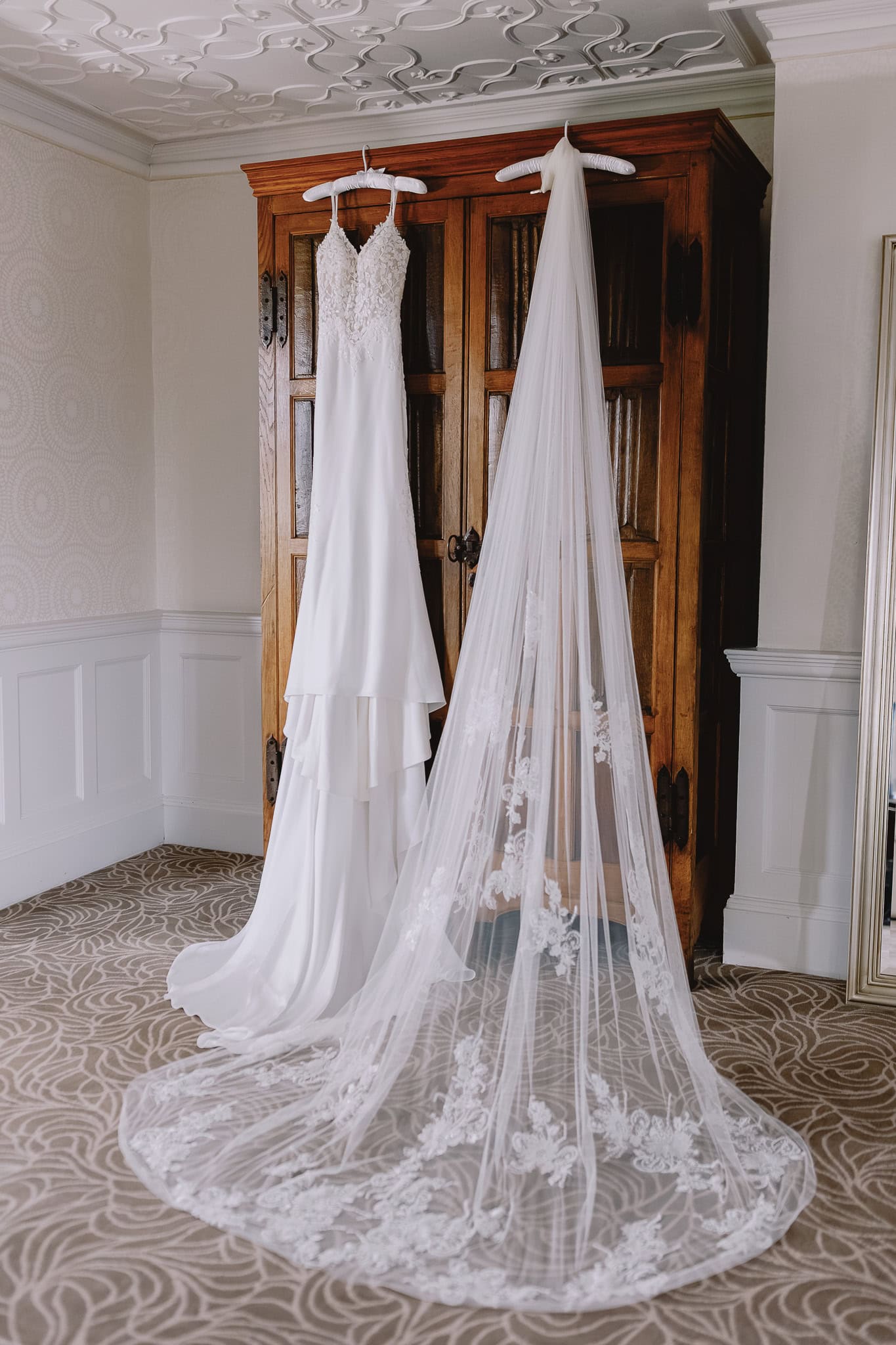 Wedding dress and lace veil hanging on a wooden wardrobe