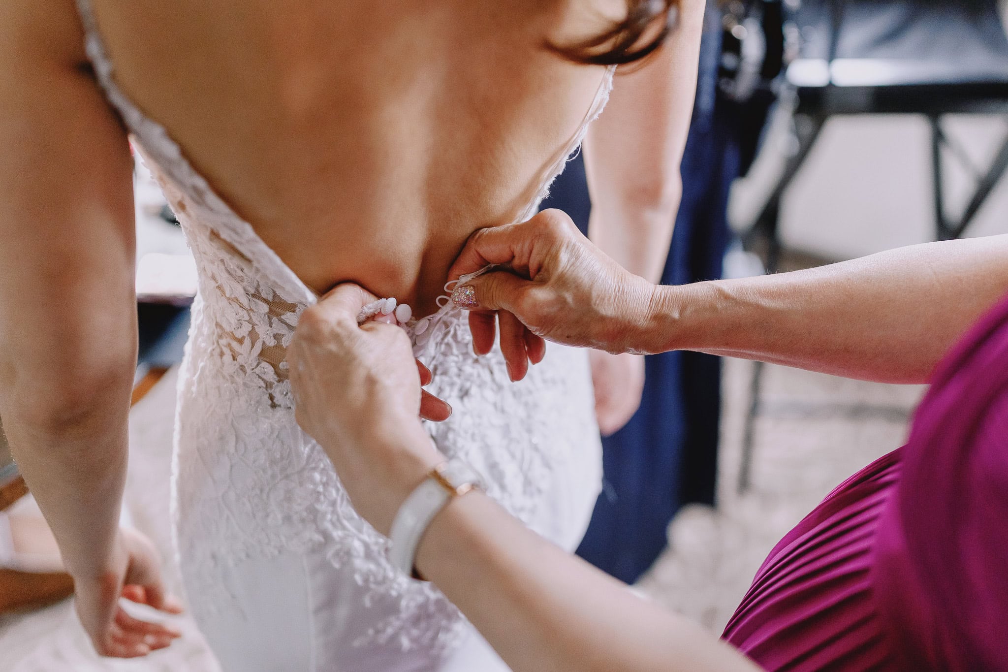 Bride getting her wedding dress laced up by a bridesmaid