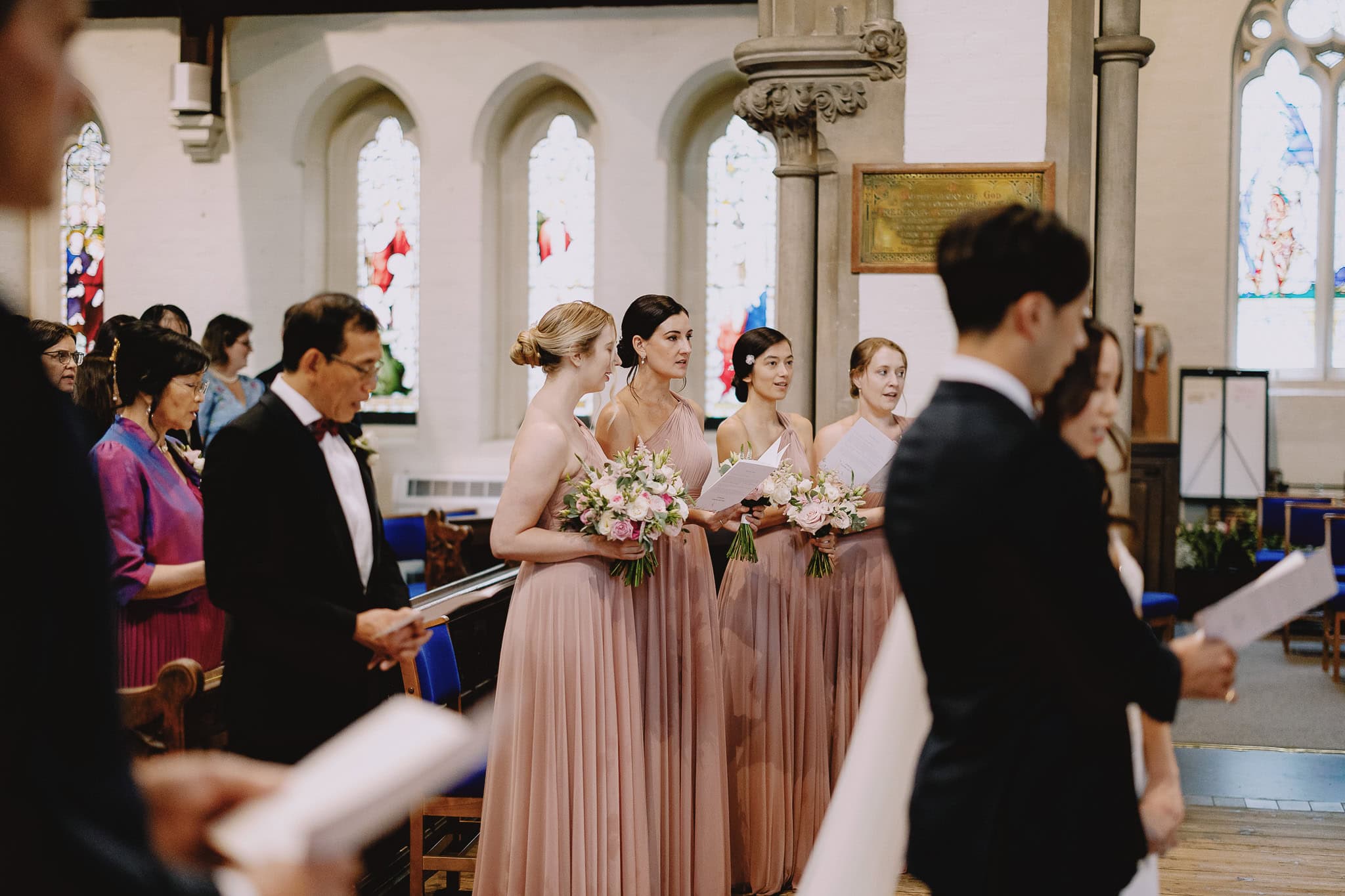 Bridesmaids in blush dresses hold organic flower bouquets at a sustainable wedding.
