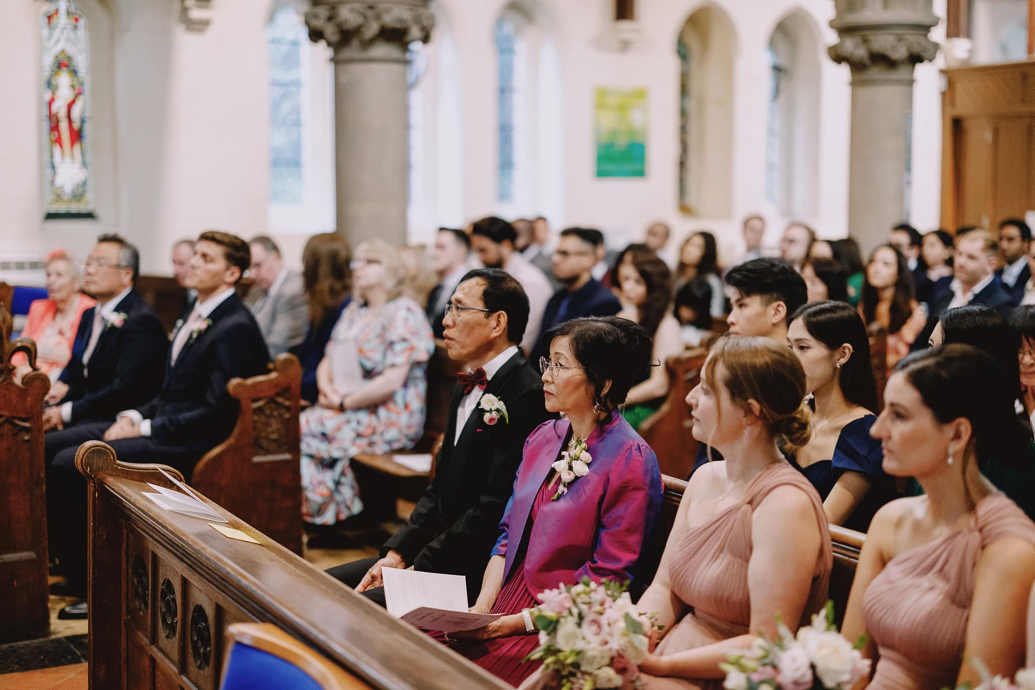 Wedding guests seated in pews during a church ceremony.