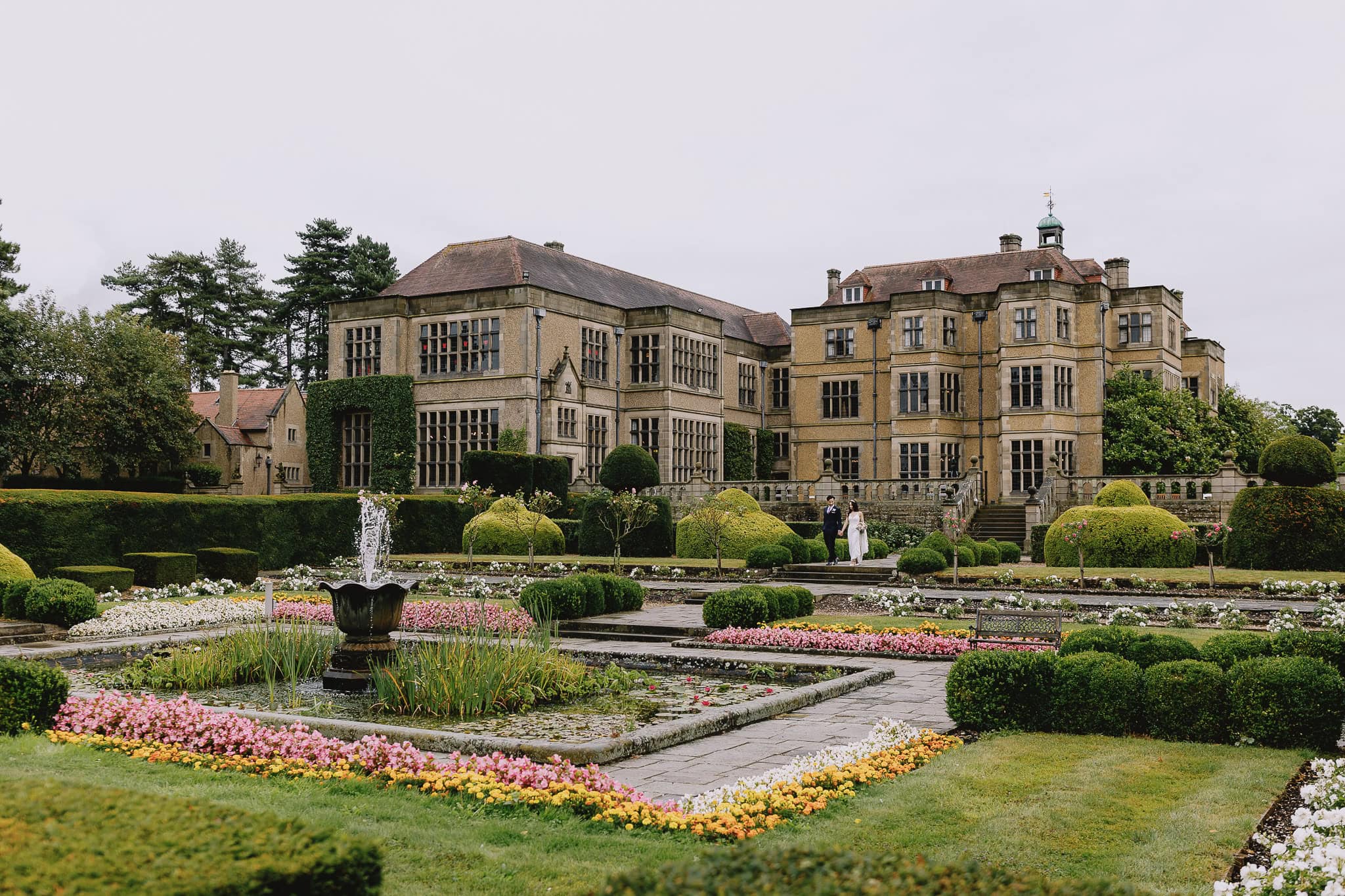 English manor house with formal gardens and a couple walking