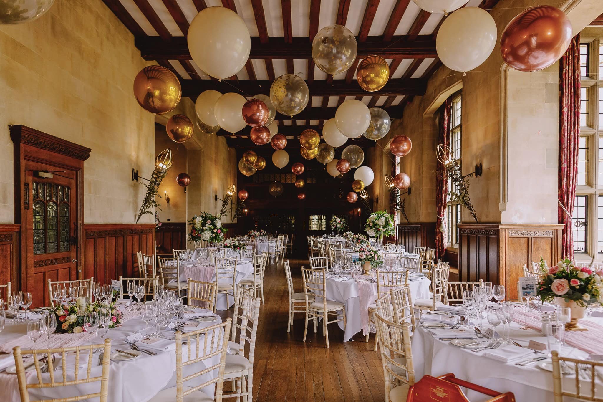 Elegant wedding reception hall with balloons and decorated tables.