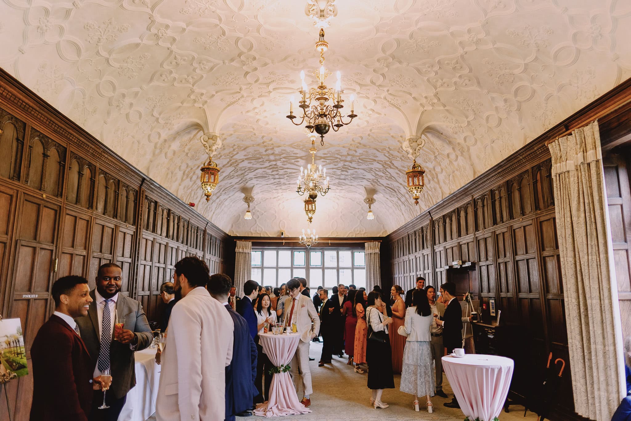 Wedding reception in a grand hall with guests mingling.