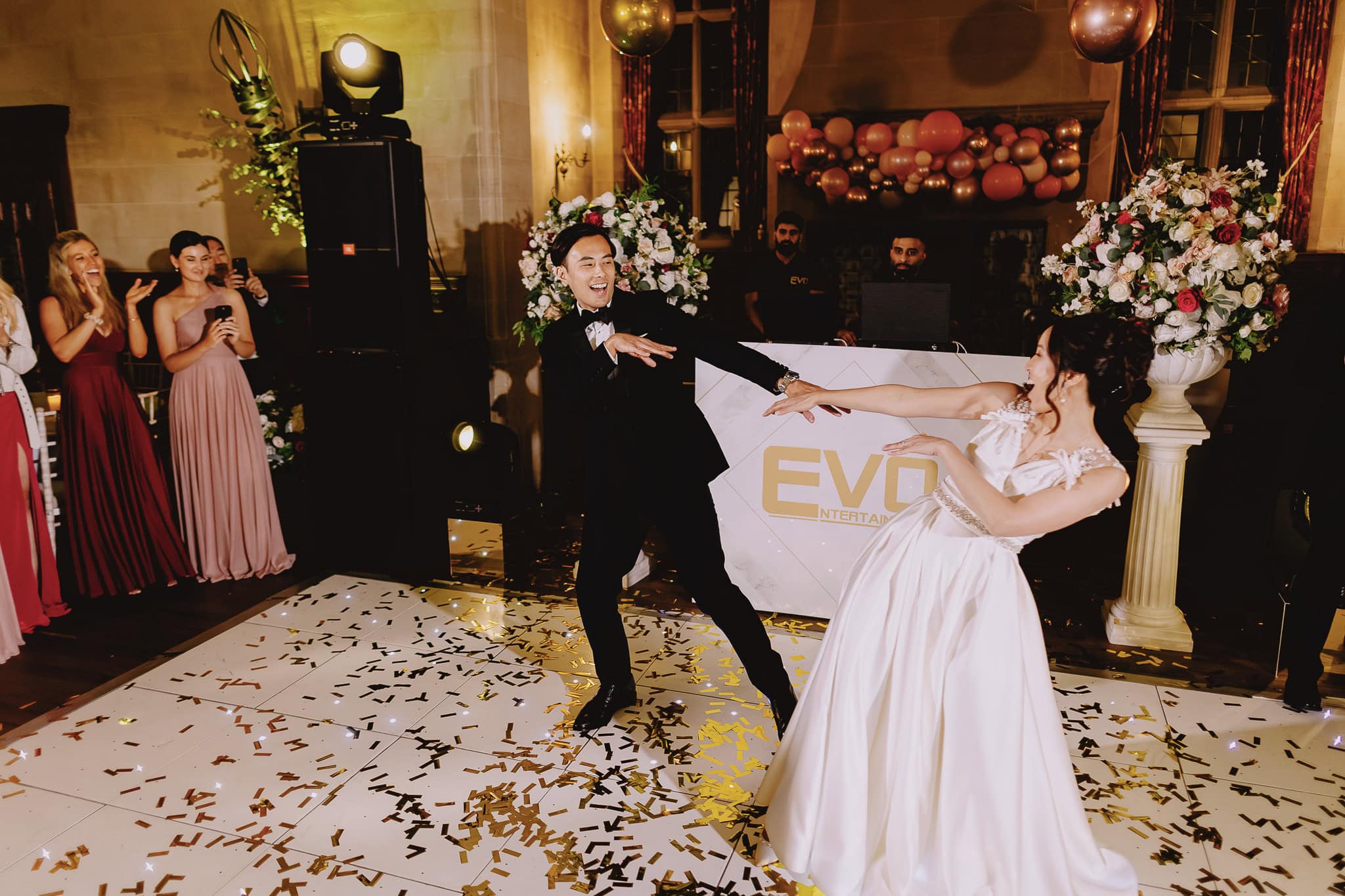 Bride and groom joyfully dancing at their wedding reception with confetti on the dance floor.