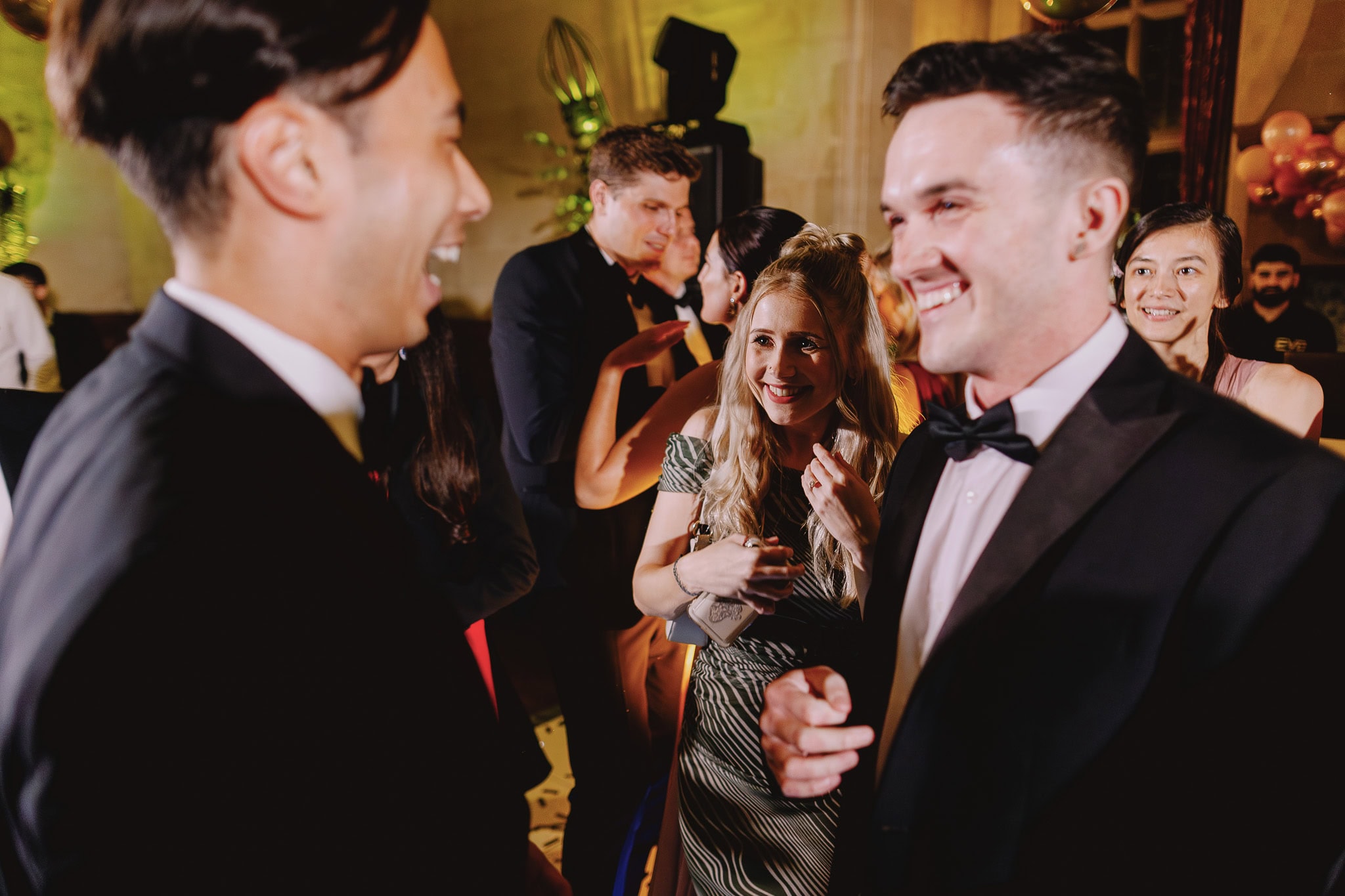 People laughing and dressed in formal wear at a party