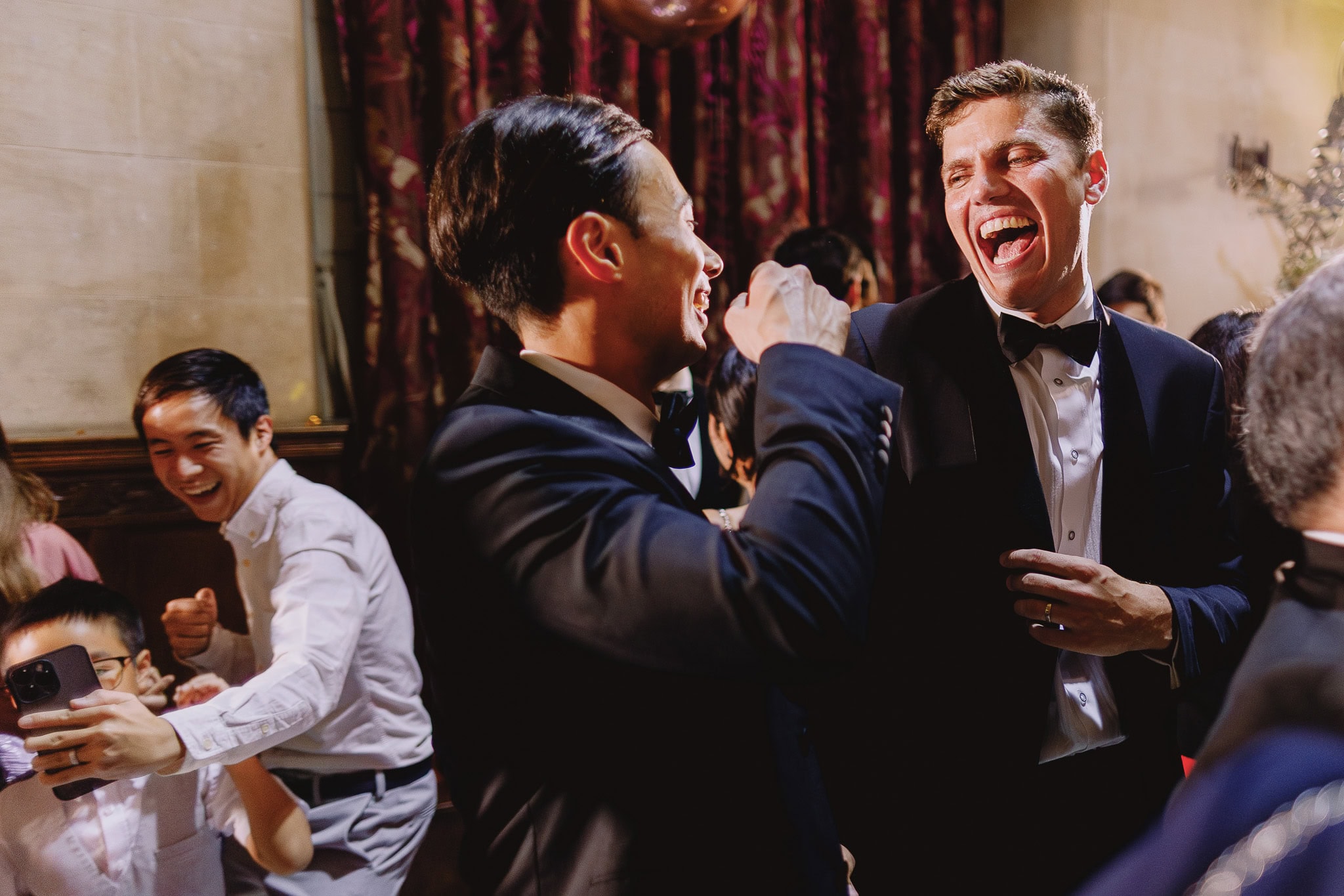 Groom and wedding guest laughing at a wedding reception