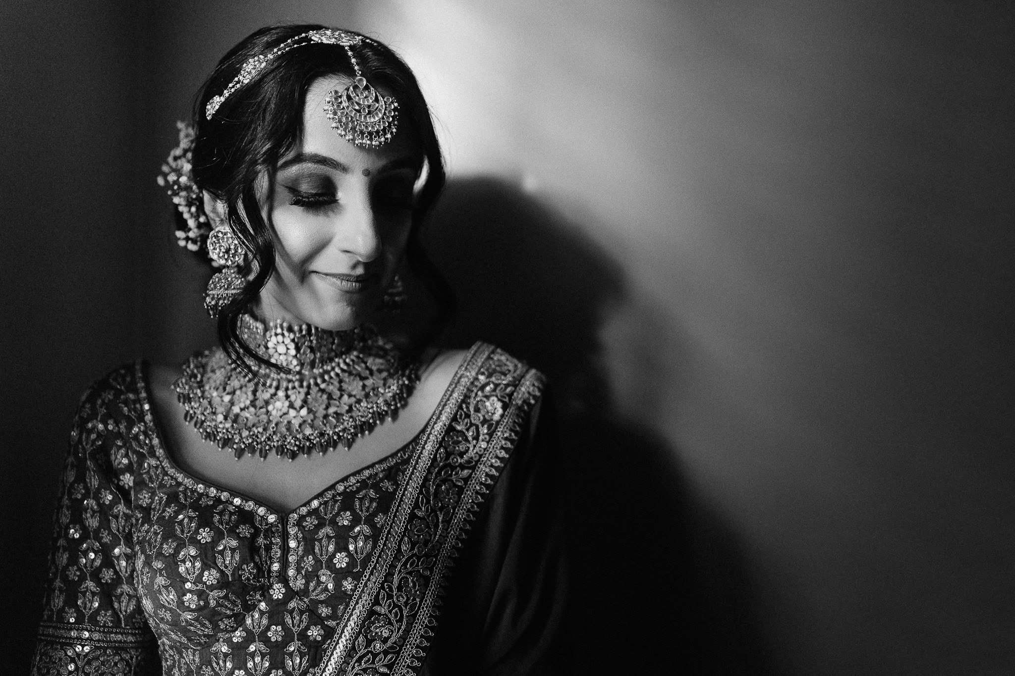 Indian bride with traditional jewelry: maang tikka, earrings, necklace, and embroidered sari.