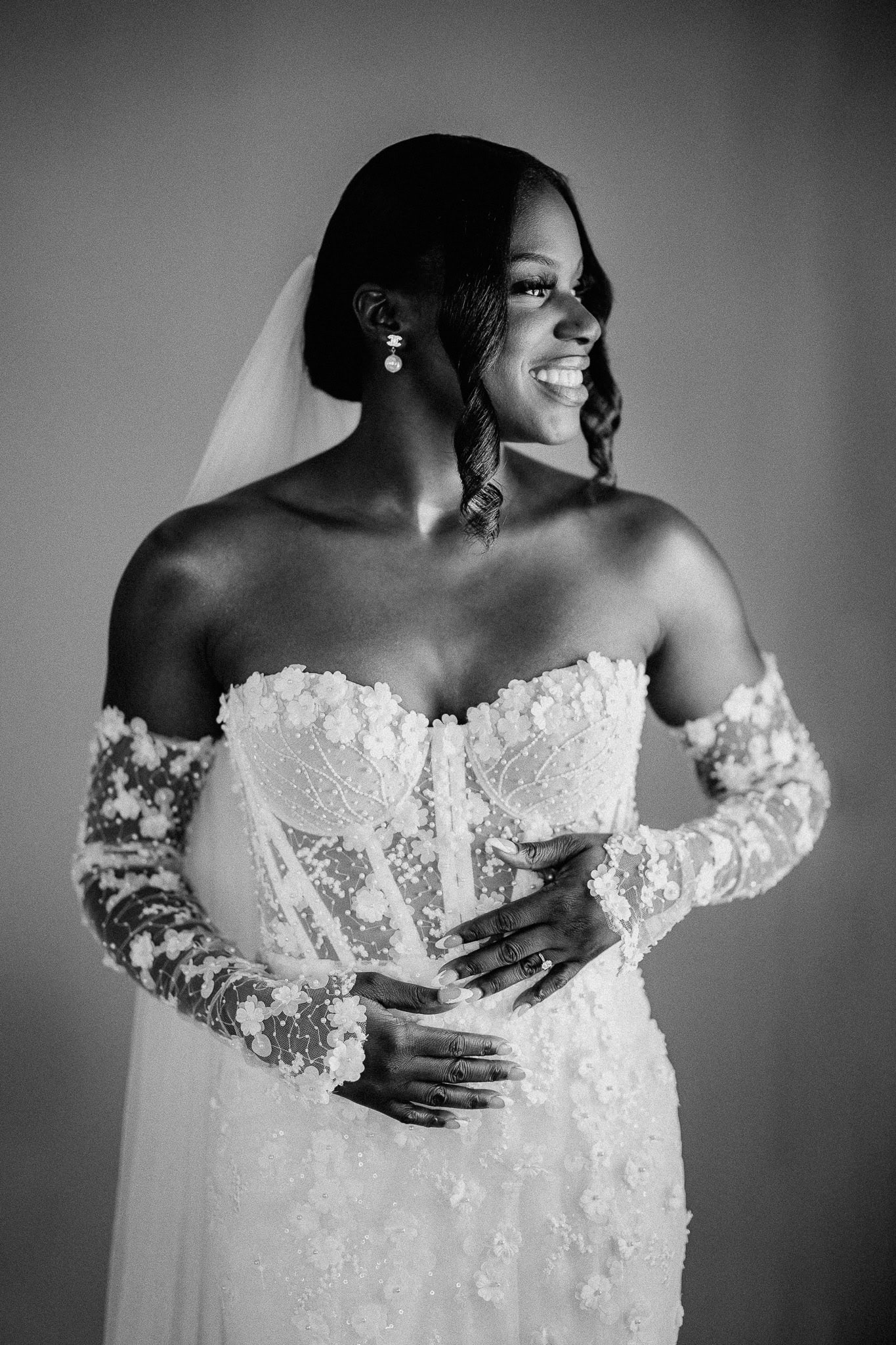 Editorial wedding photography: Bride in a detailed strapless gown with floral embellishments and long sleeves.