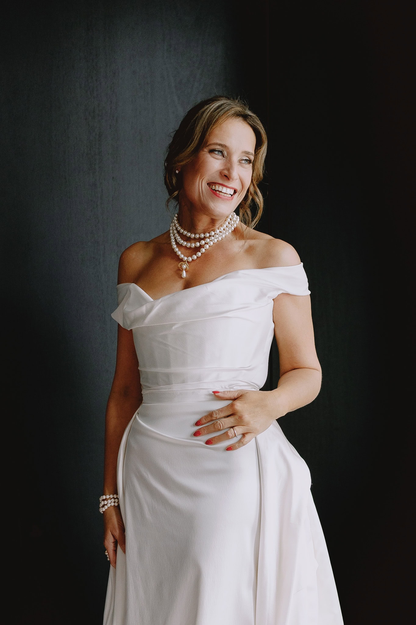 Editorial wedding photography: Bride in white dress and pearls smiles