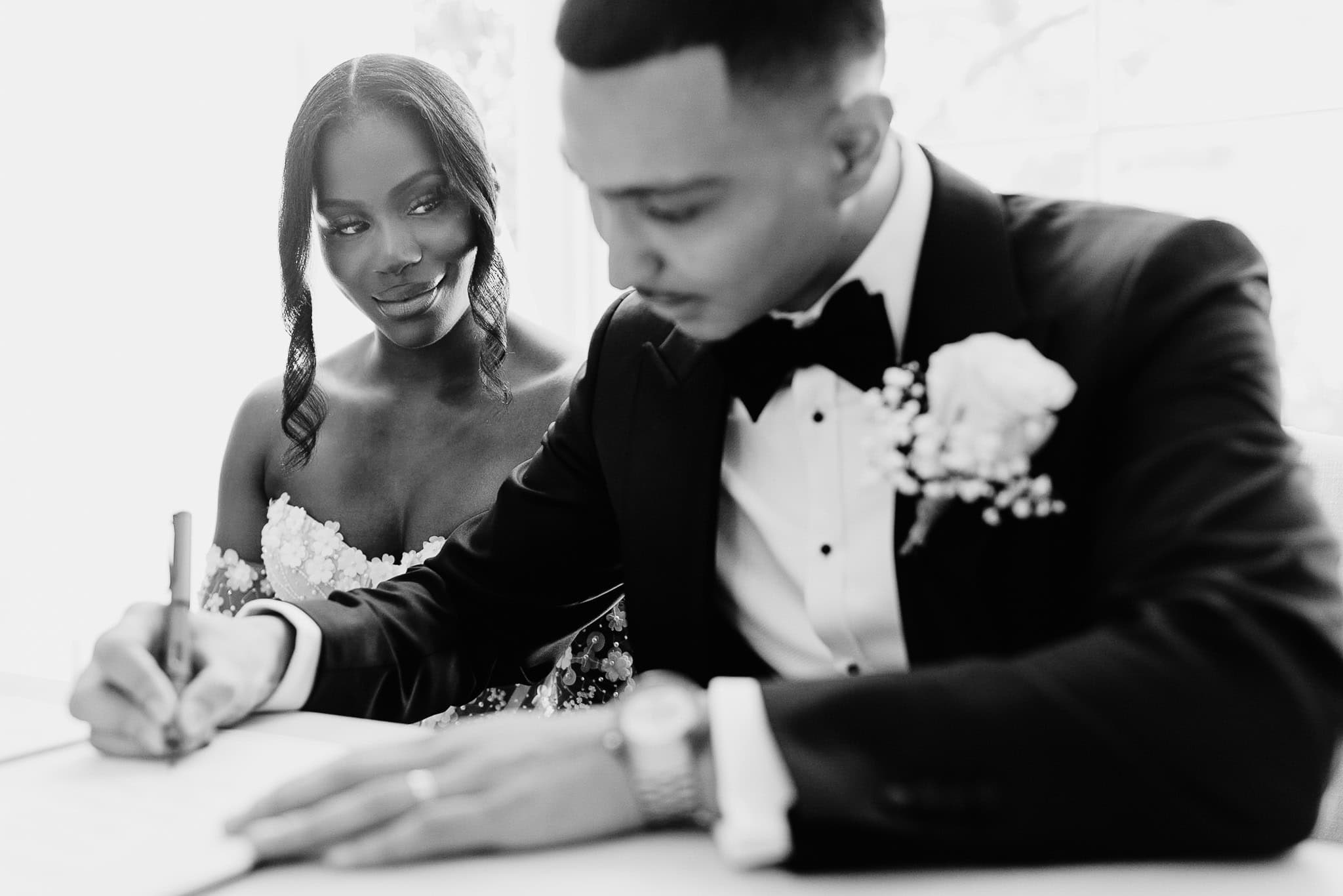 Black and white wedding photography portfolio: Couple signing marriage license