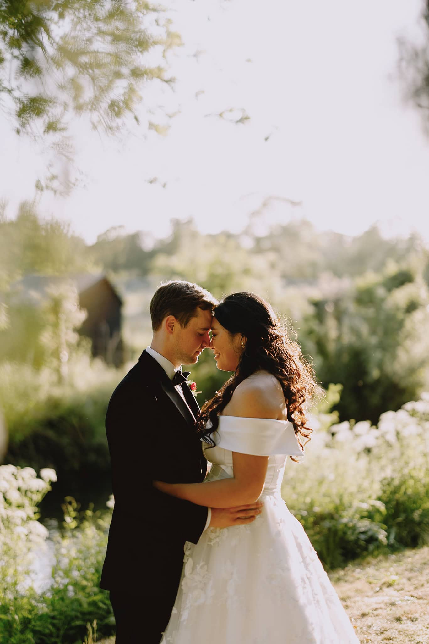 Bride and groom embrace outdoors at sunset, golden hour wedding photography